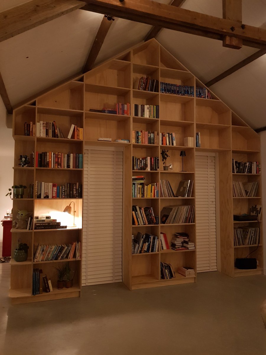 Wandvullende boekenkast in de vorm van een huis met zadeldak